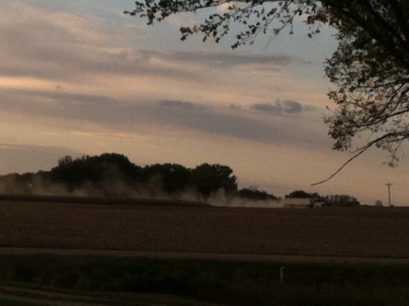 Grain trucks kicked up rolling clouds of dust in the northwest wind