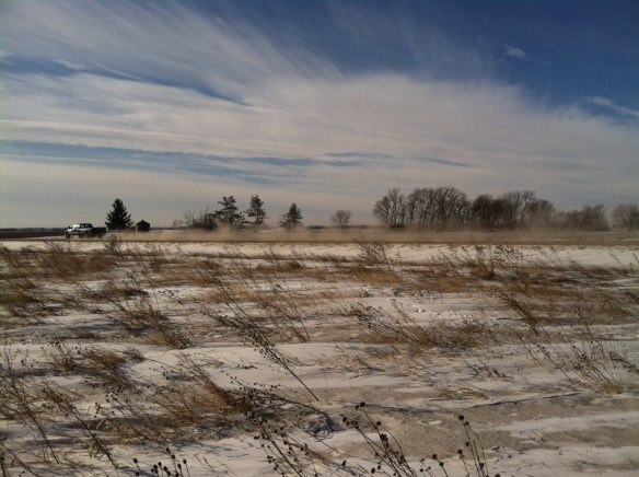 A plume of light brown road dust forms as a truck passes by.